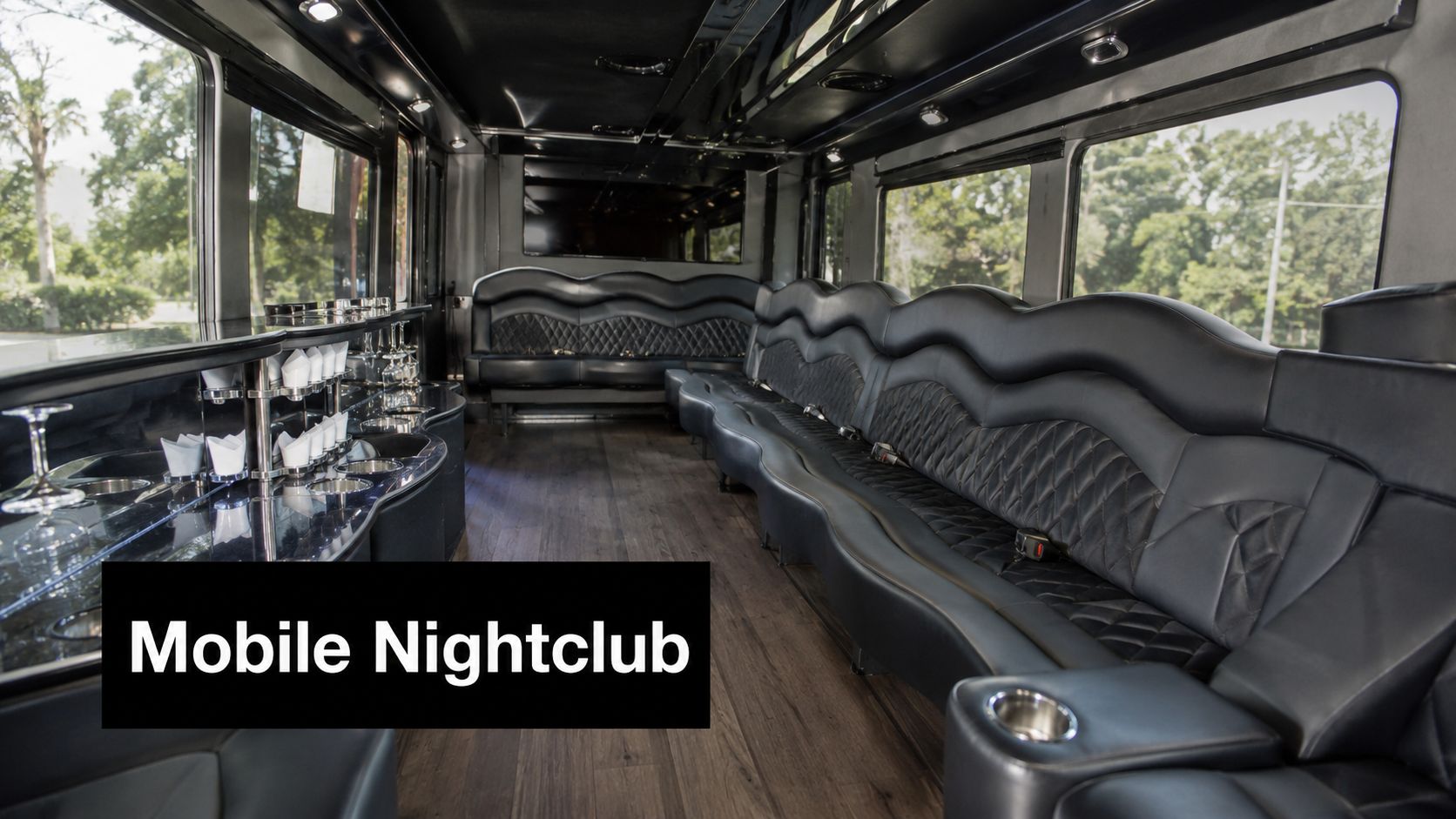 Interior view of a modern luxury stretch limousine featuring black quilted leather seats and a bar area.